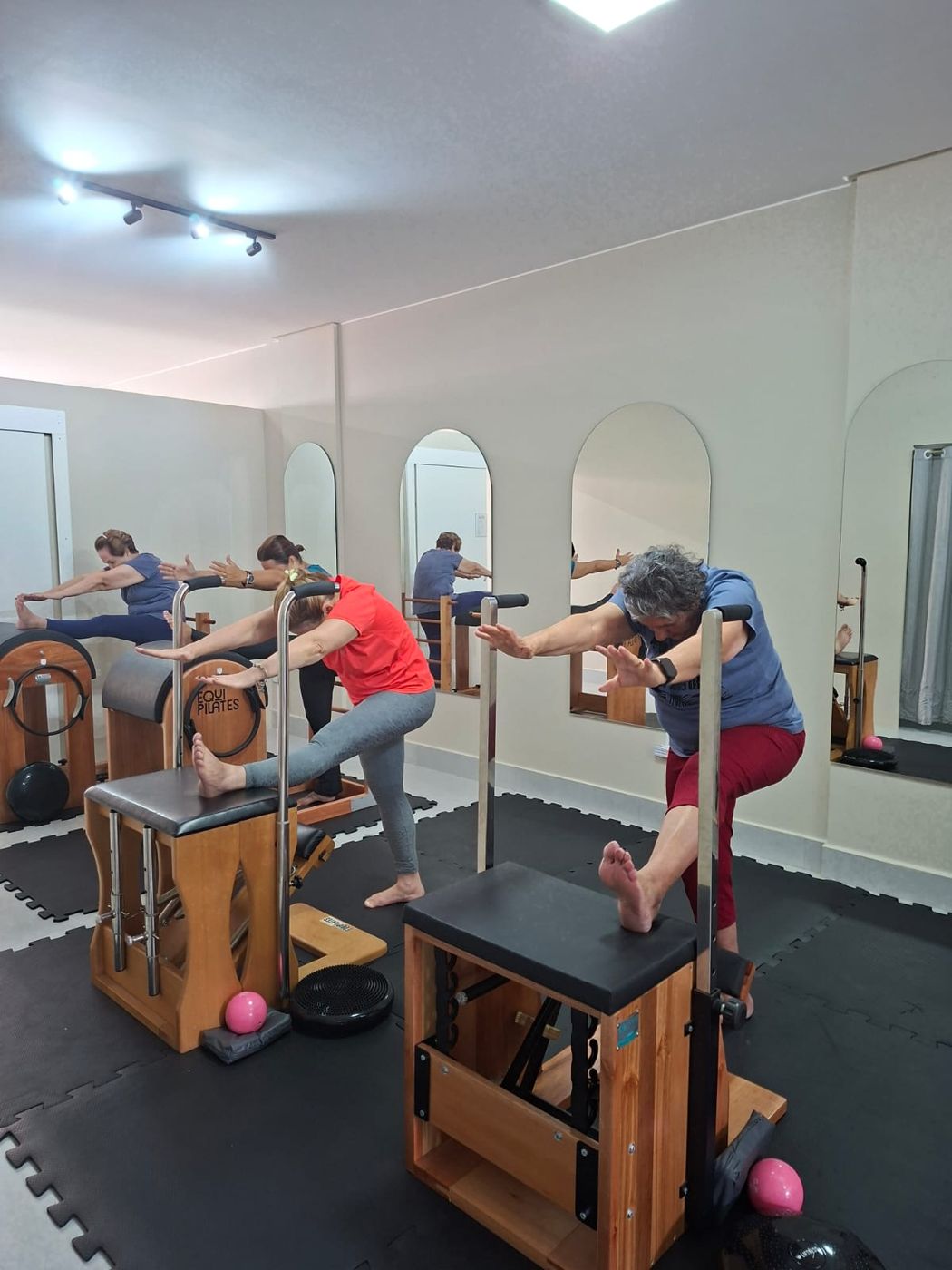 Pessoas em exercício nas cadeiras de Pilates